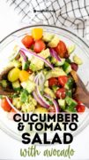 A white plate full of the cucumber tomato avocado salad and a black and white tea towel.