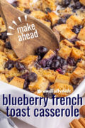 A Pinterest image of a wooden spoon scooping out the blueberry french toast casserole.