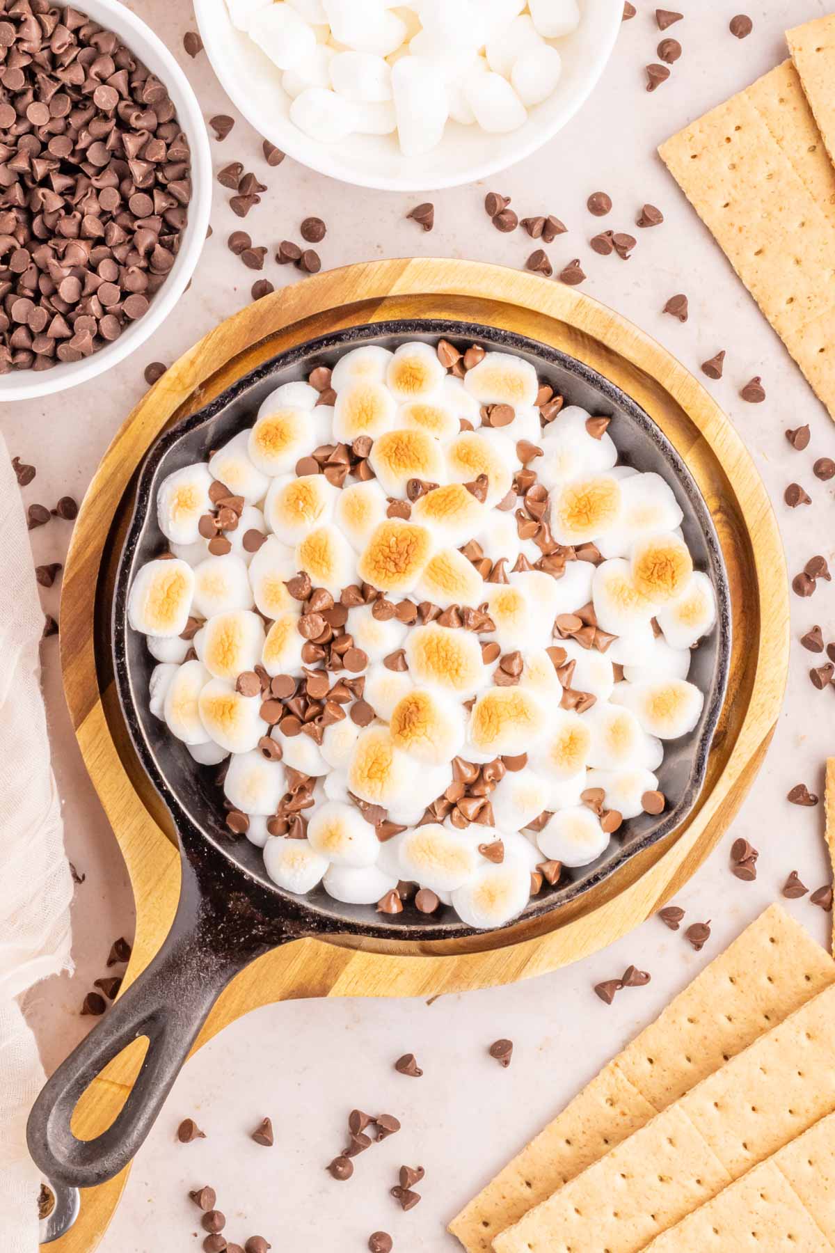 An overhead image of a cast iron skillet filled with a gooey s'mores dip.