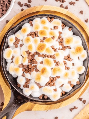 An overhead image of a cast iron skillet filled with a gooey s'mores dip.