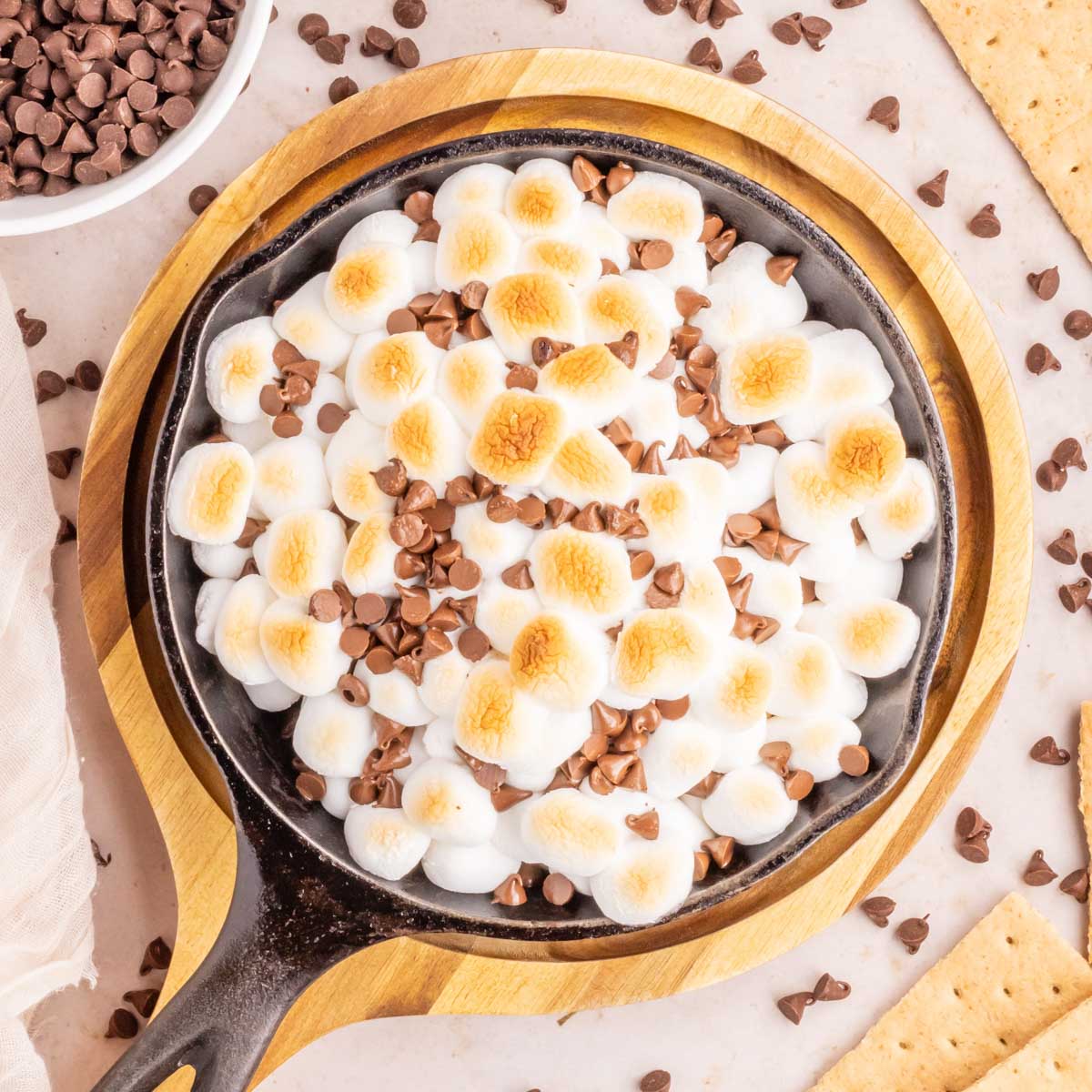 An overhead image of a cast iron skillet filled with a gooey s'mores dip.