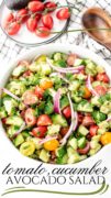A fukll white serving bowl full of a tossed cucumber tomato, avocado and red onion salad.