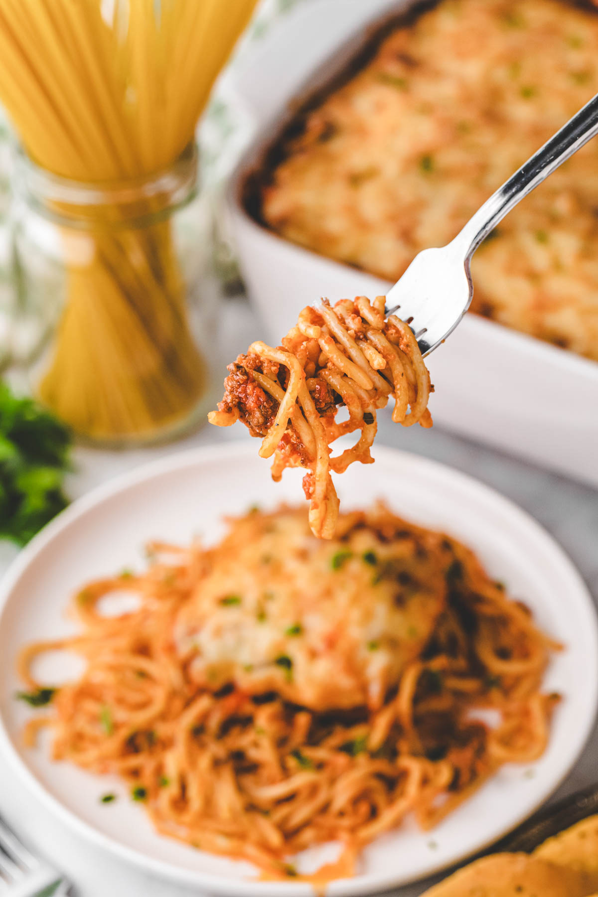 A fork filled with a bite of baked spaghetti.