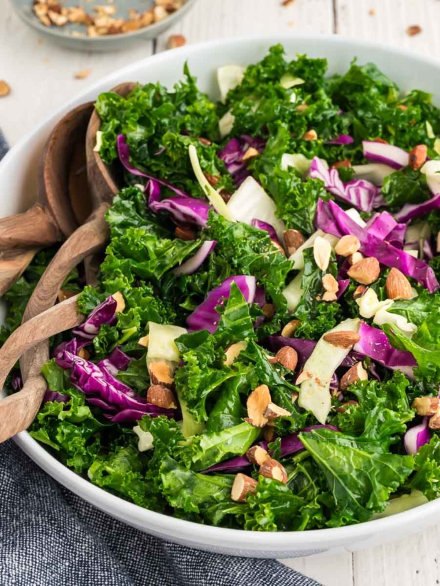 A kale crunch salad in a white bowl topped with toasted almonds.