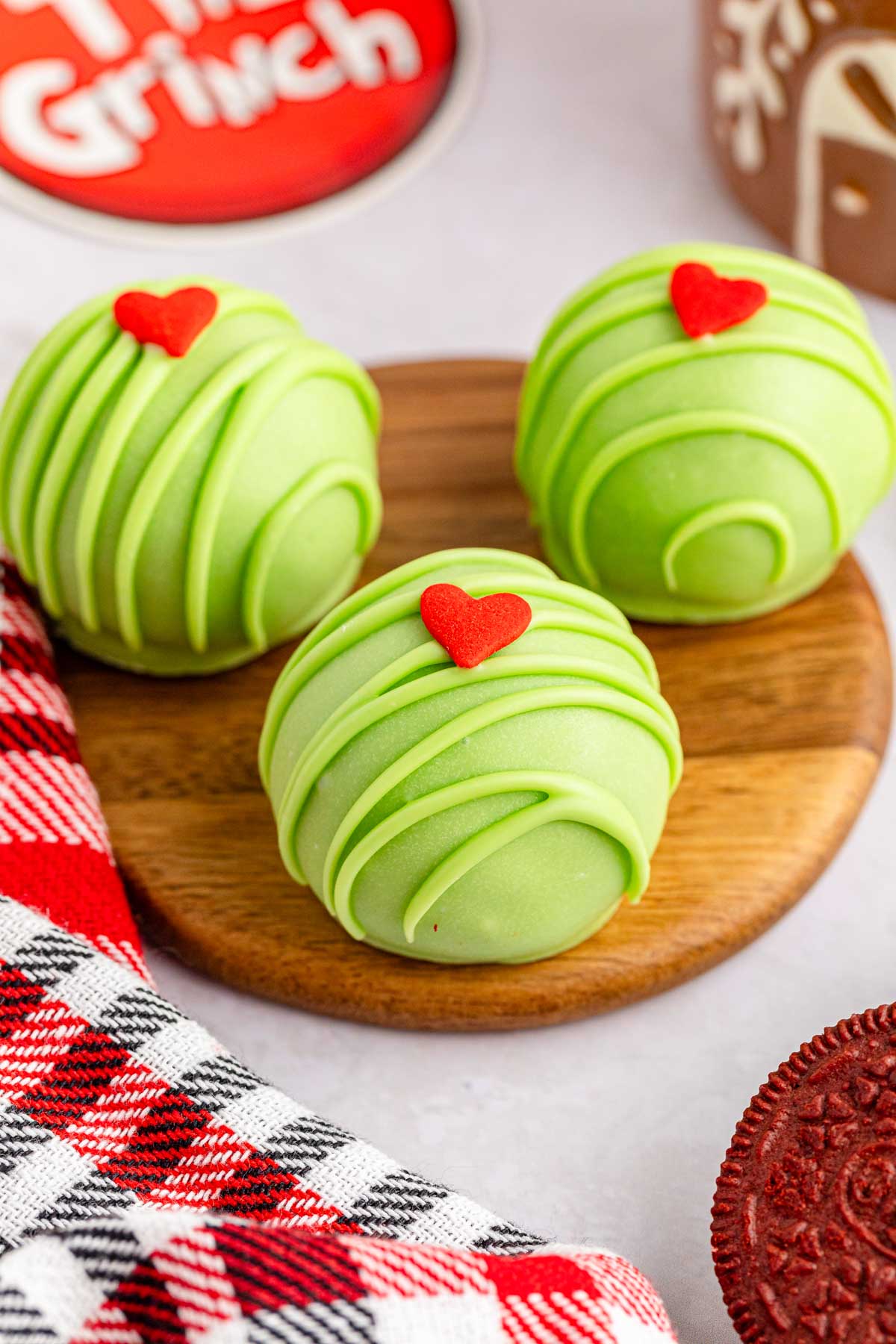 Three Grinch Christmas truffles on a wooden plate.