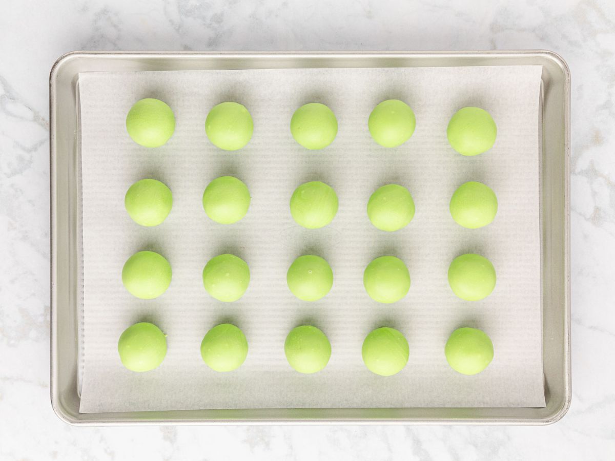 Red velvet oreo balls dipped in green candy melts and placed on parchment lined tray to set.