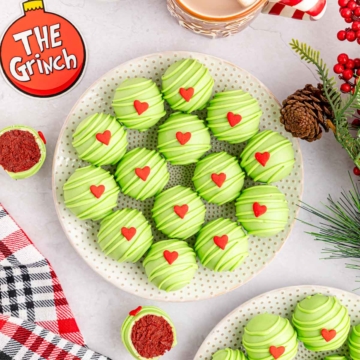 A serving plate of Grinch red velvet Oreo Balls decorated with bright green candy melts and a candy heart.