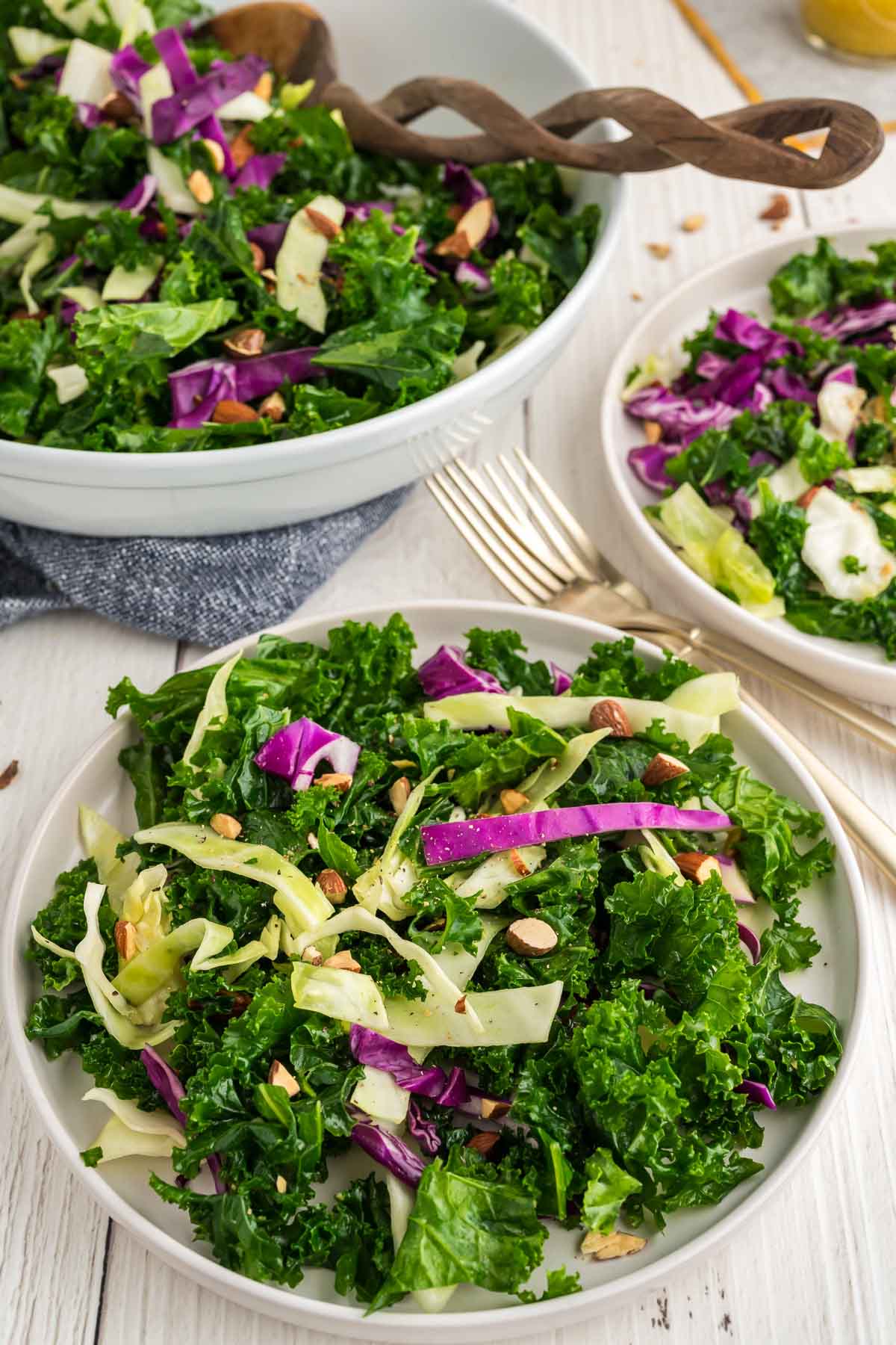 A plate copycat chick-fil-a kale salad on a white plate with the serving bowl of salad behind it.