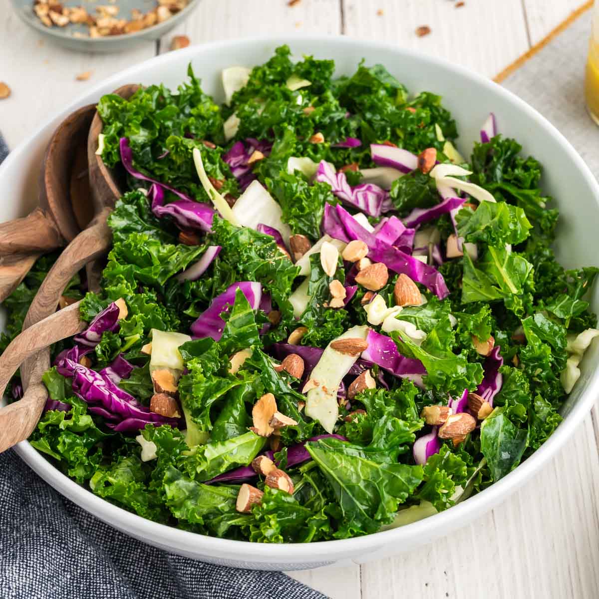 A kale crunch salad in a white bowl topped with toasted almonds.