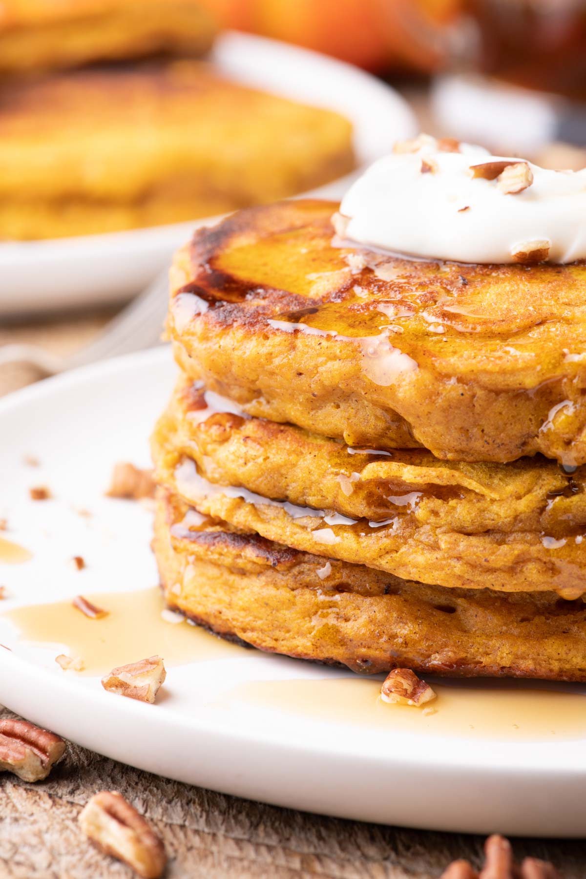 Pumpkin pancakes topped with maple syrup, whipped cream, and pecans.