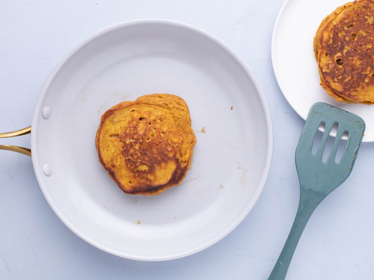 Pumpkin pancake being cooked in a buttered skillet.