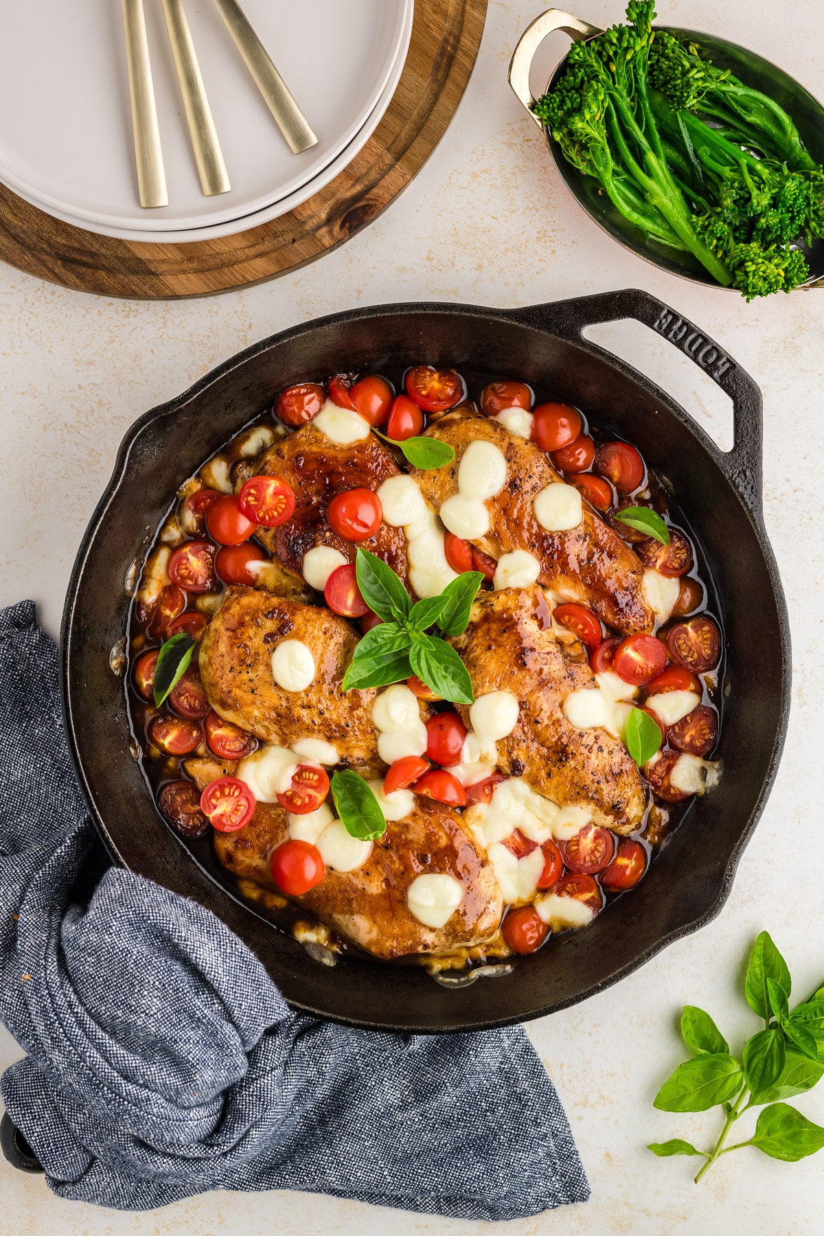 A blue tea towel wrapped around a cast iron skillet of chicken caprese.