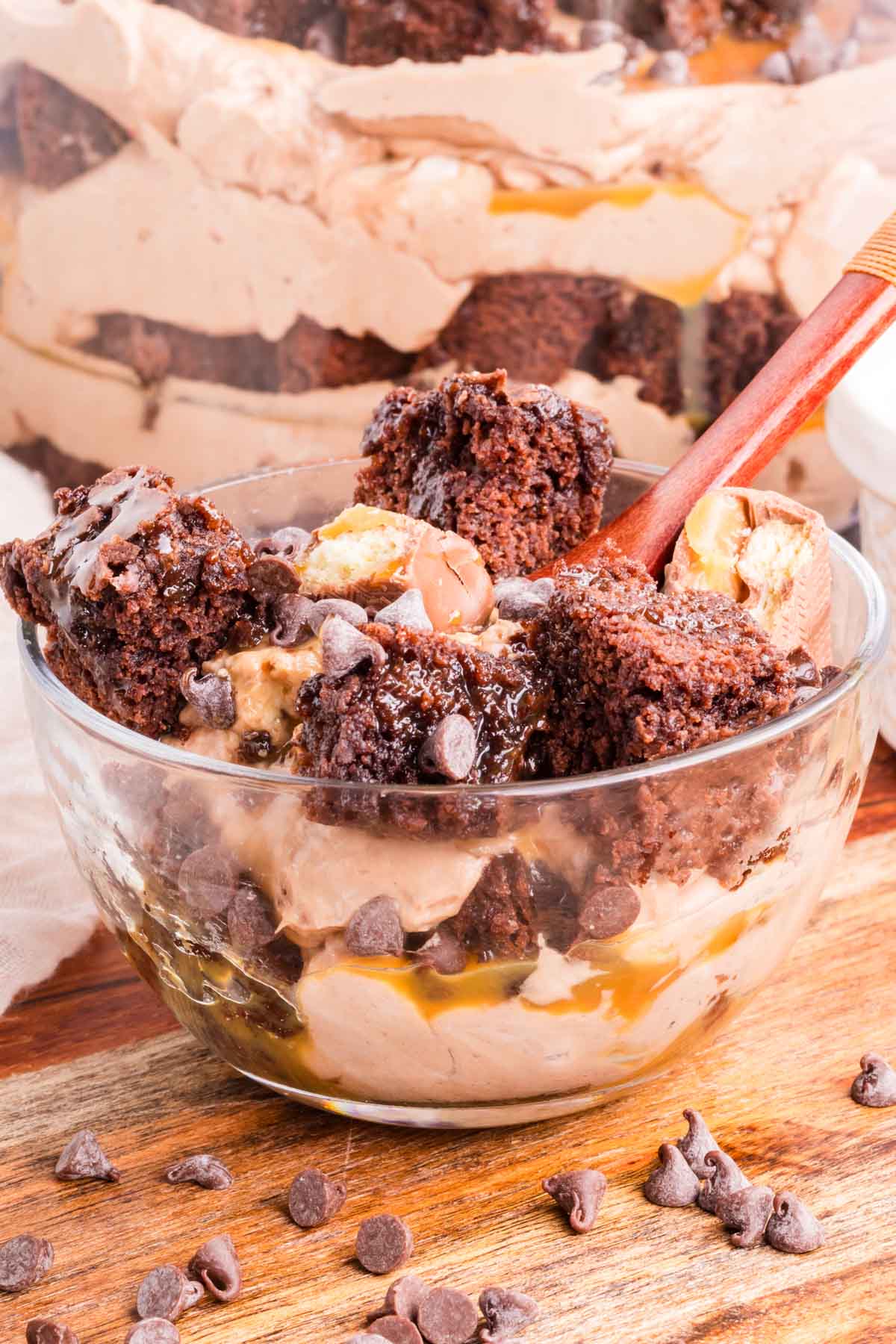 An individual serving of brownie cheesecake layered dessert in a clear bowl.