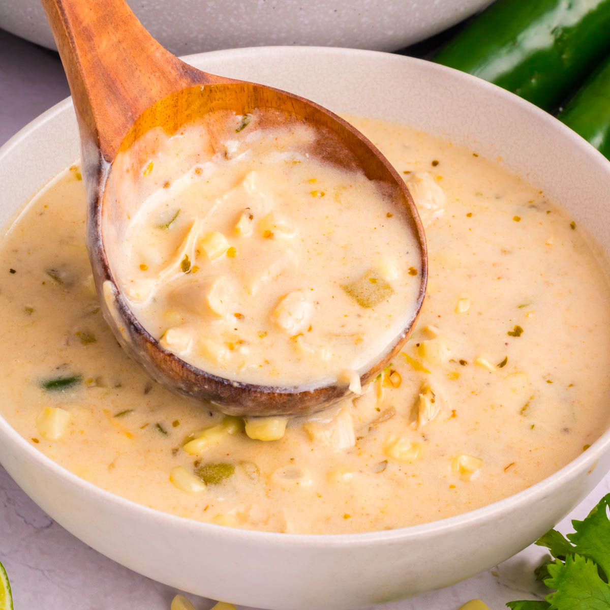 A wooden ladle full of Mexican street corn white chicken chili.