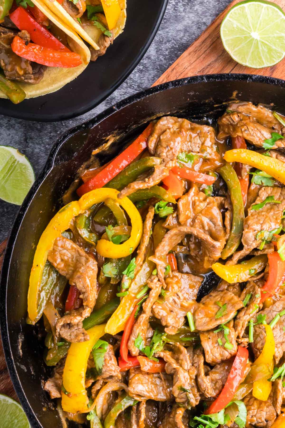 Steak, peppers and onions cooked in fajita seasoning in a skillet.