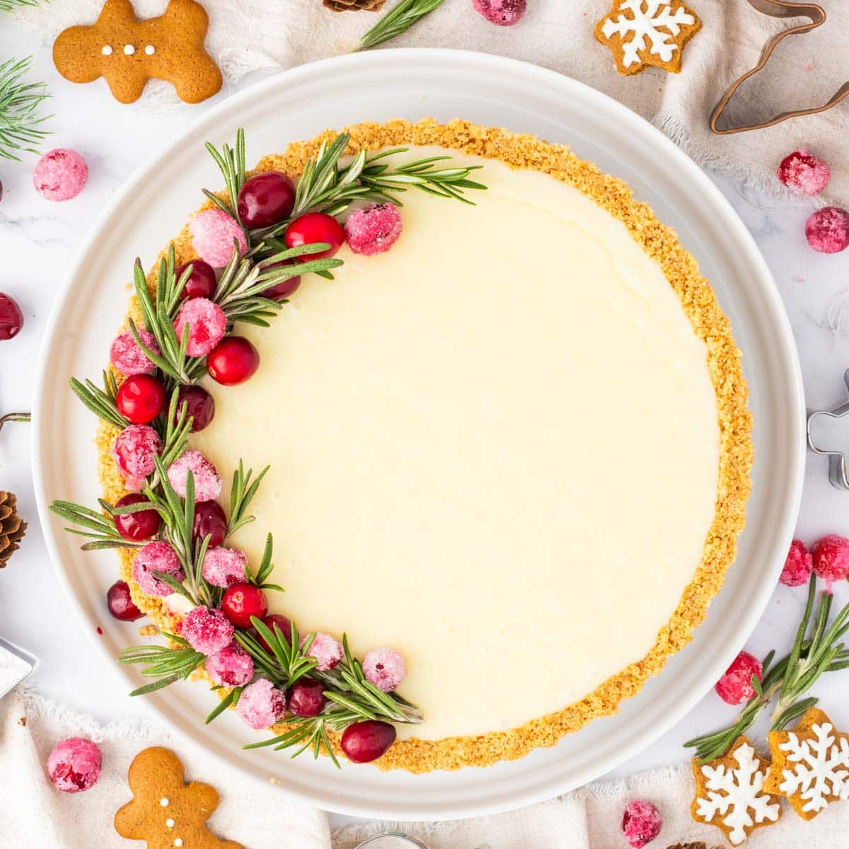 A white chocolate tart garnished with sugared cranberries and rosemary.