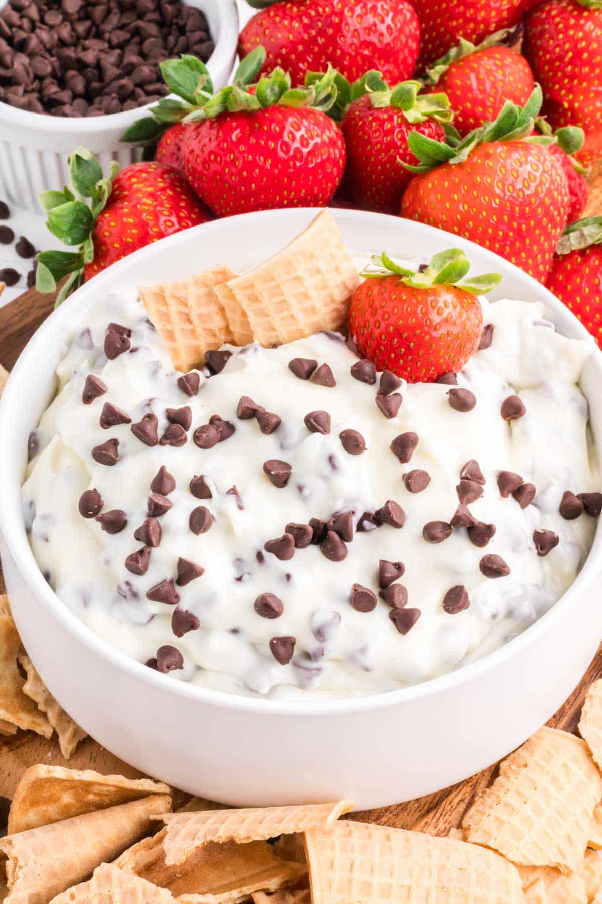 Cannoli dip topped with mini chocolate chips and garnished with waffle cone pieces and a strawberry.