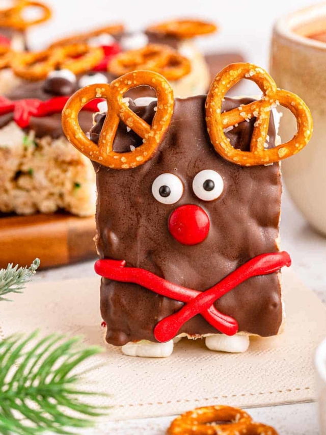 A reindeer rice krispies treat standing up with Christmas decor in the background.