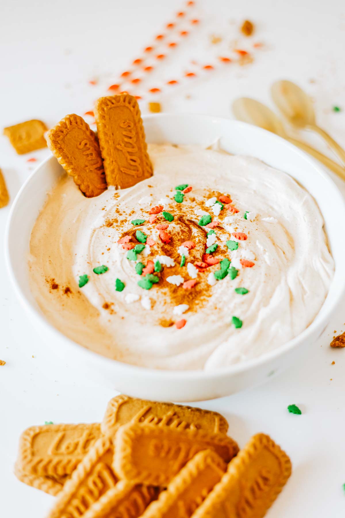 Eggnog Dip in a white bowl garnished with festive sprinkles and biscoff cookies.