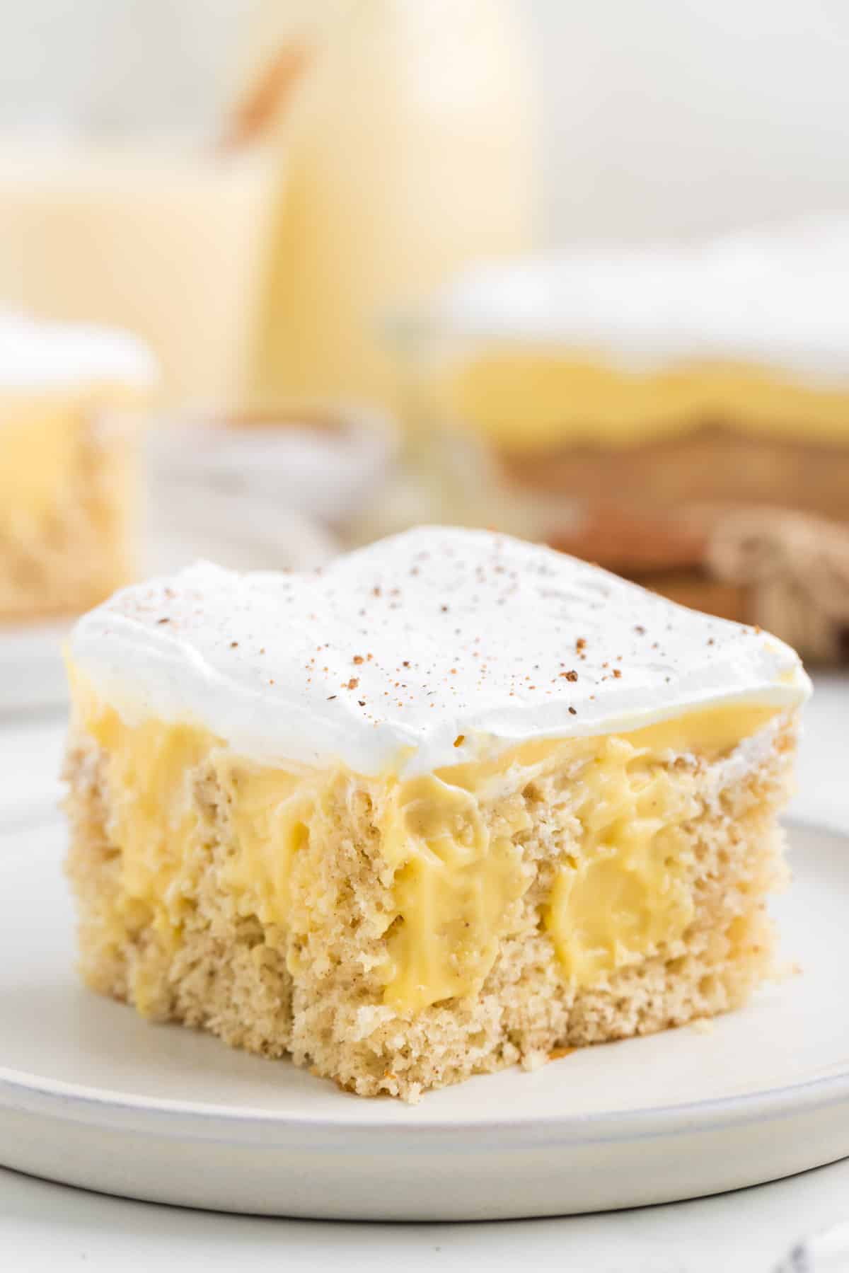 Eggnog poke cake with layers of eggnog pudding sliced and served on a white plate.