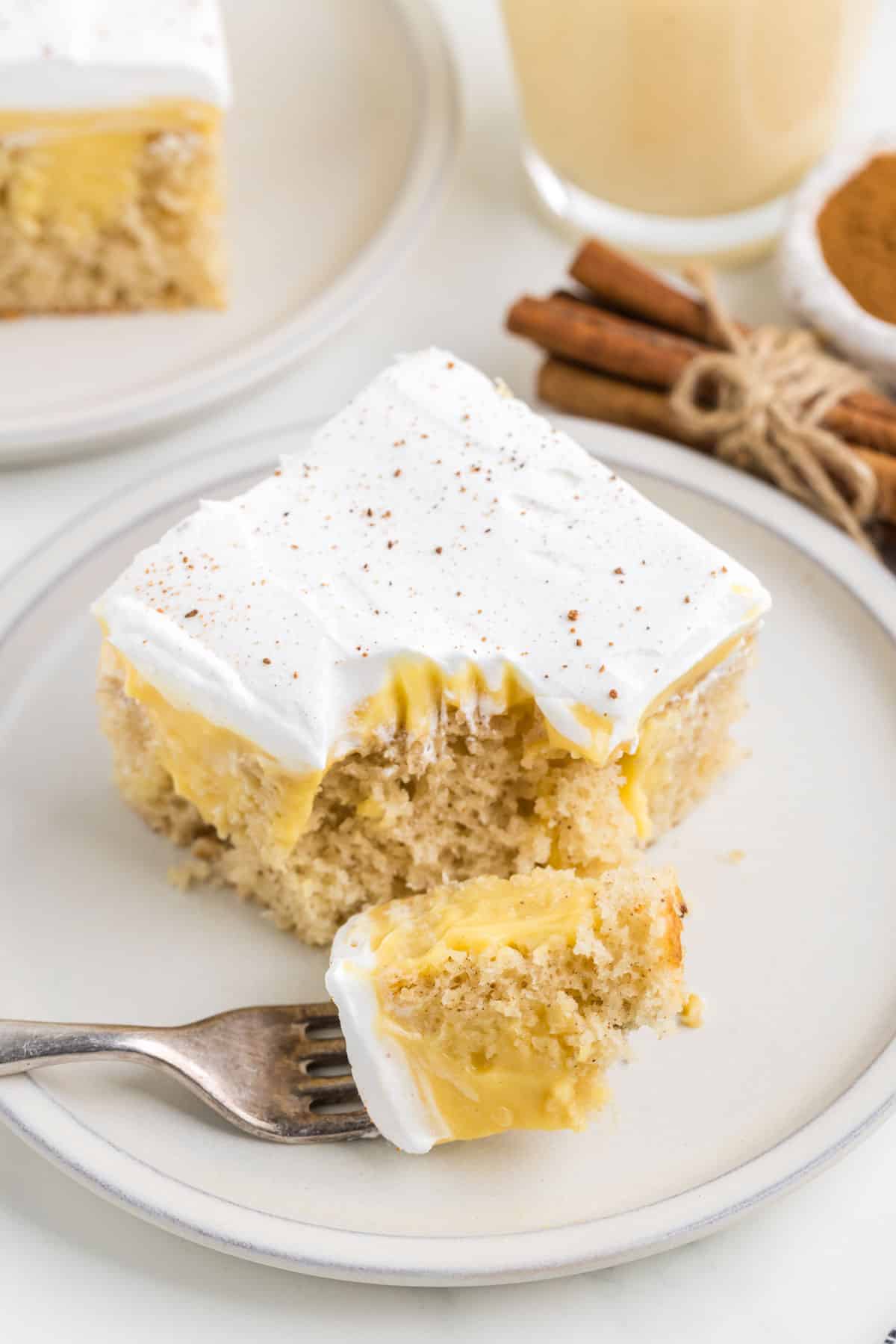 A fork with a bite of eggnog poke cake removed and sat on the plate.