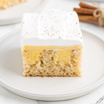 A slice of eggnog poke cake with a cinnamon stick garnish.