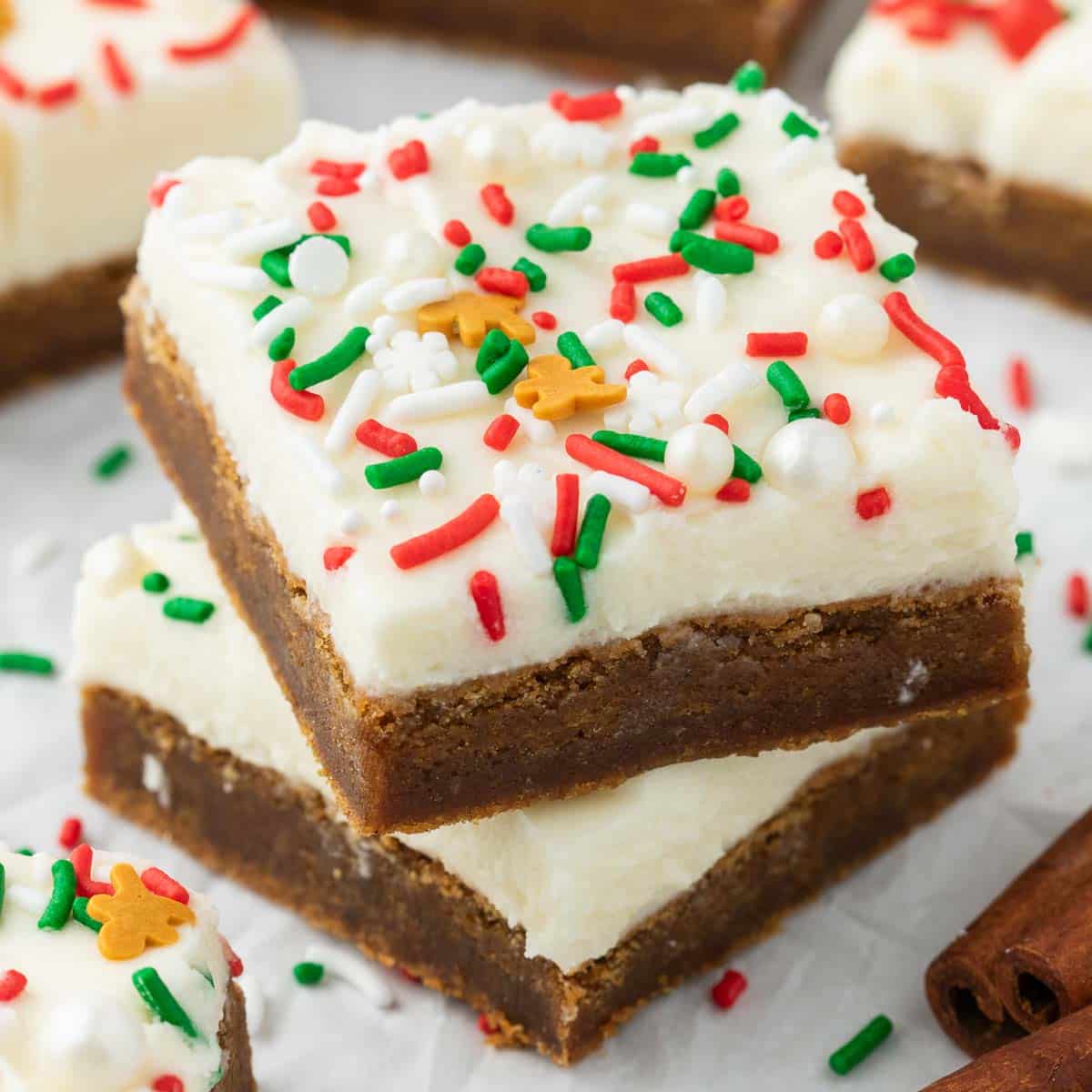 Gingerbread cookie bars on a white parchment lined tray with holiday sprinkles on top and scatter for decor.