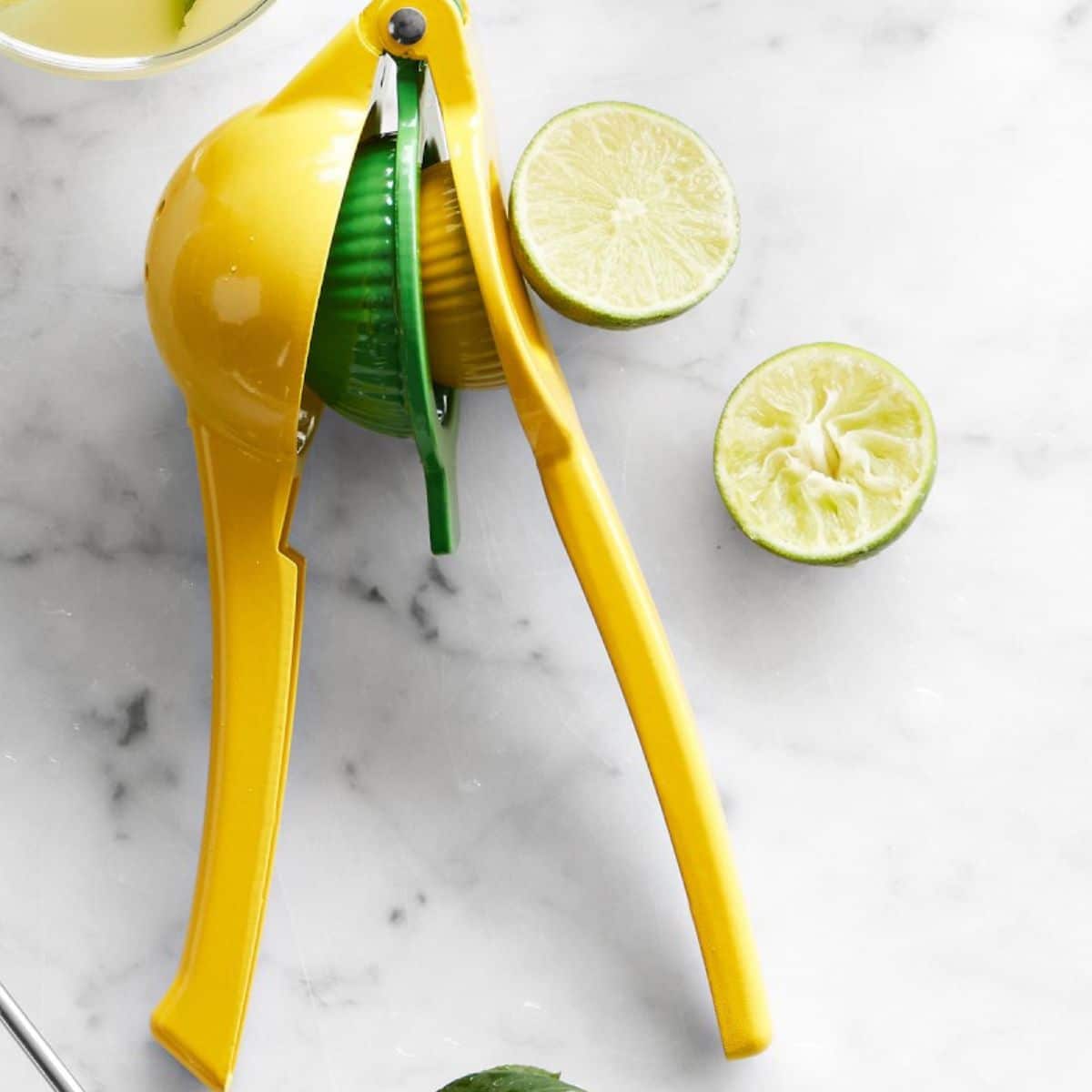 A citrus press or lemon or lime squeezer with a cut lime to the side.