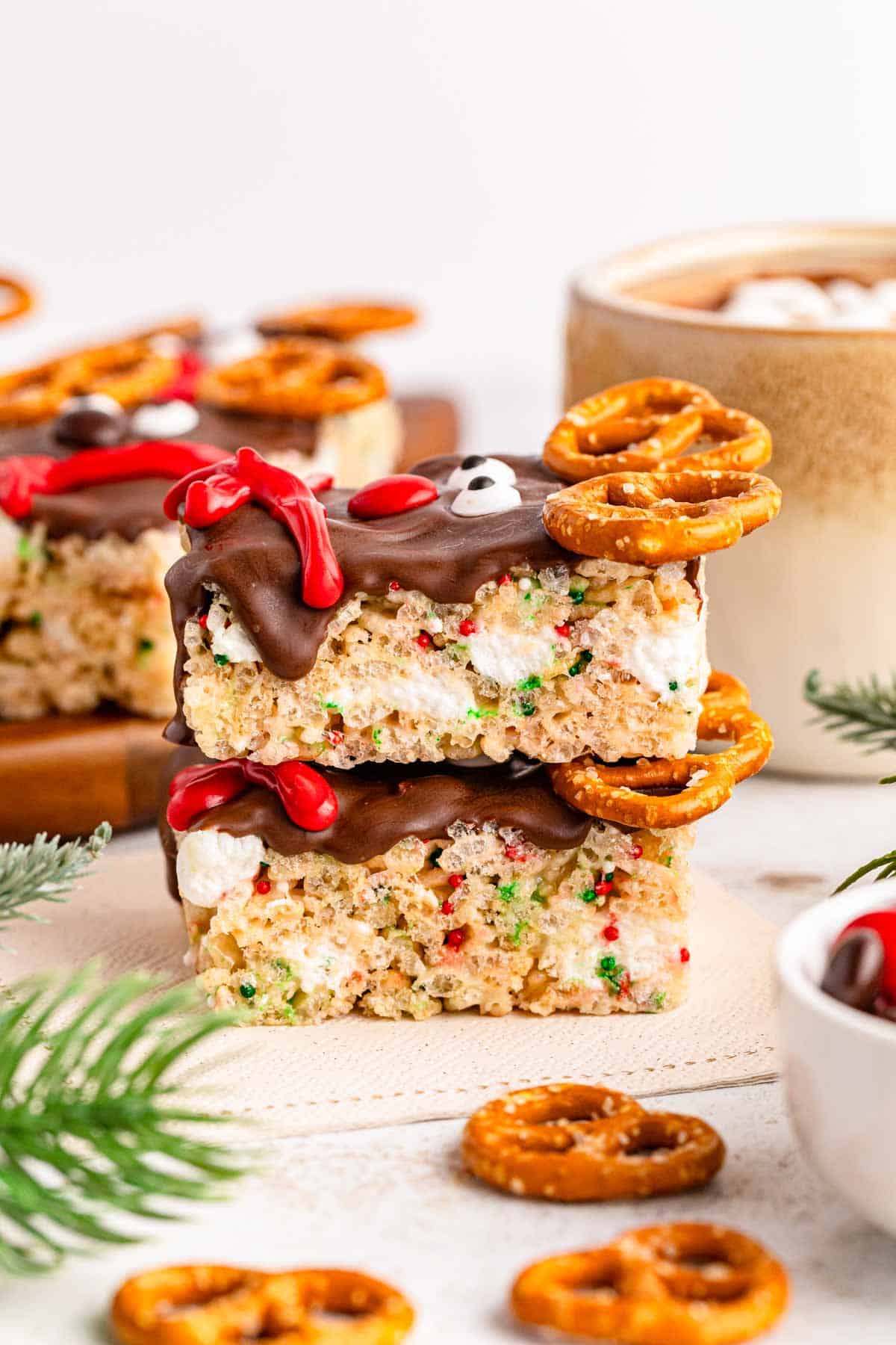 Two stacked reindeer rice krispies with snowman holiday decor in the background.