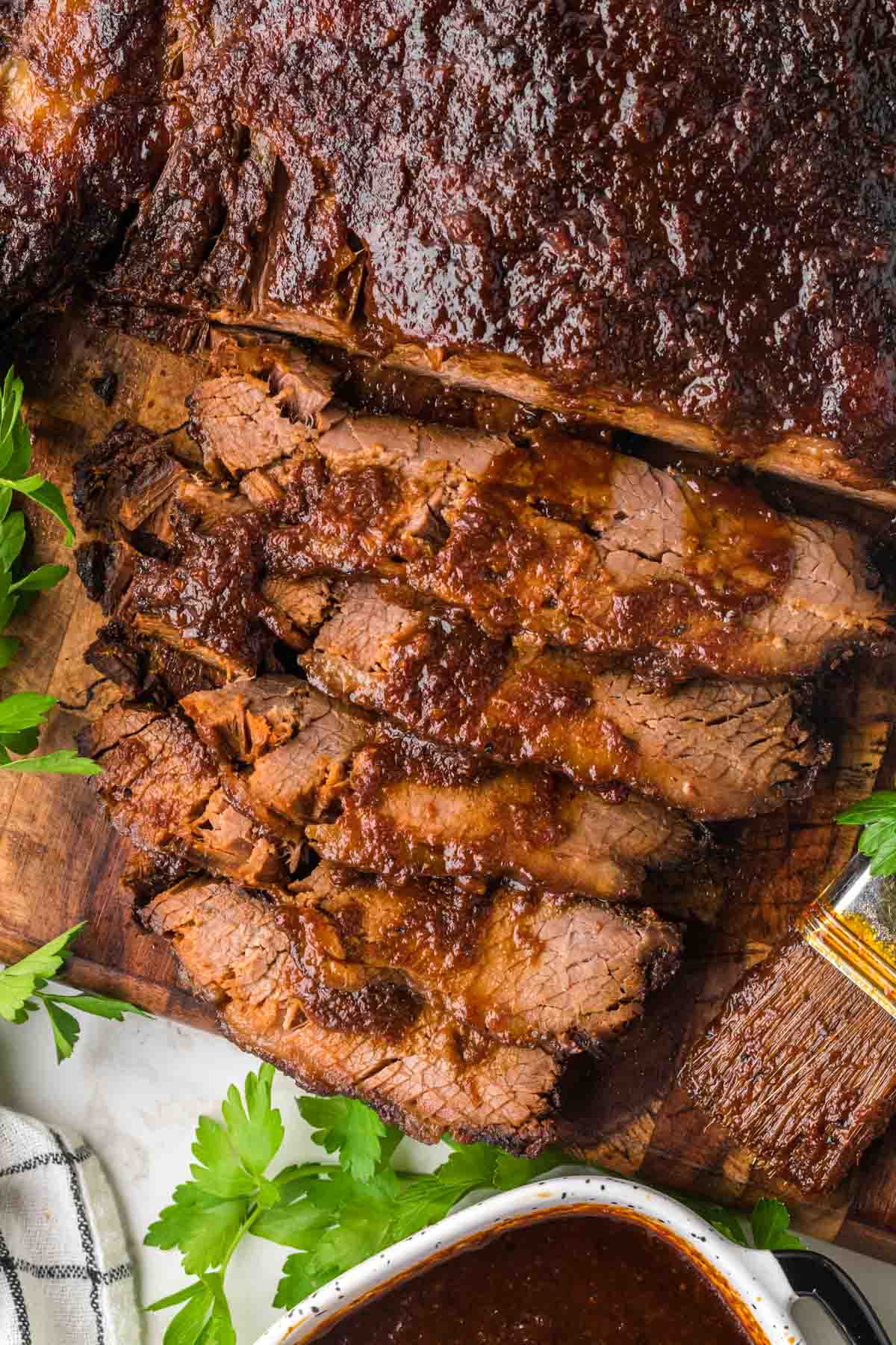 Sliced BBQ beef brisket with sauce drizzled on top.