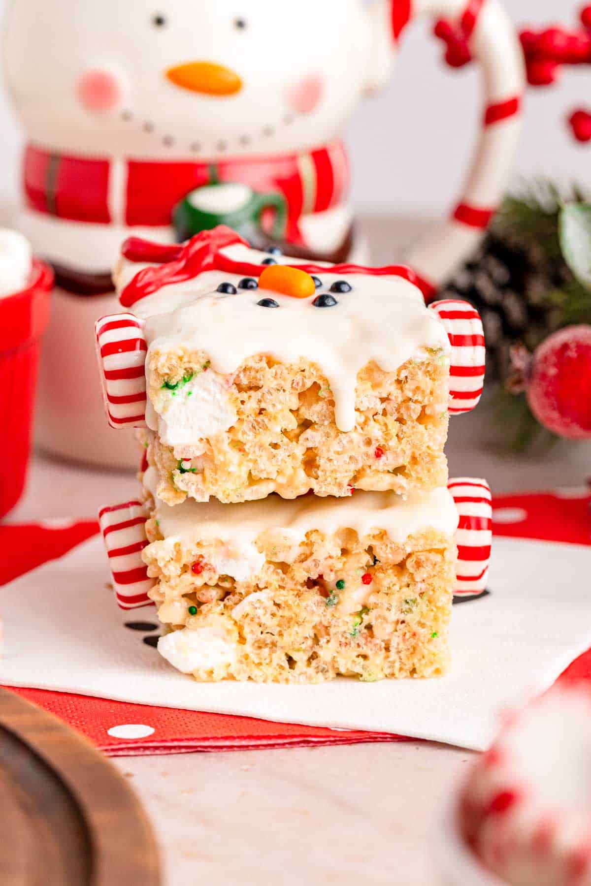 Two stacked snowmen rice krispies with snowman holiday decor in the background.