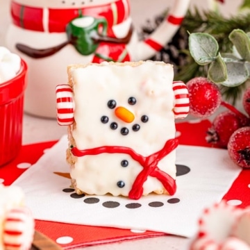 A snowman decorated rice krispie treat set on festive white and red napkins.