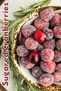 A closeup of a gold rimmed bowl with festive rosemary springs and sugared cranberroes.