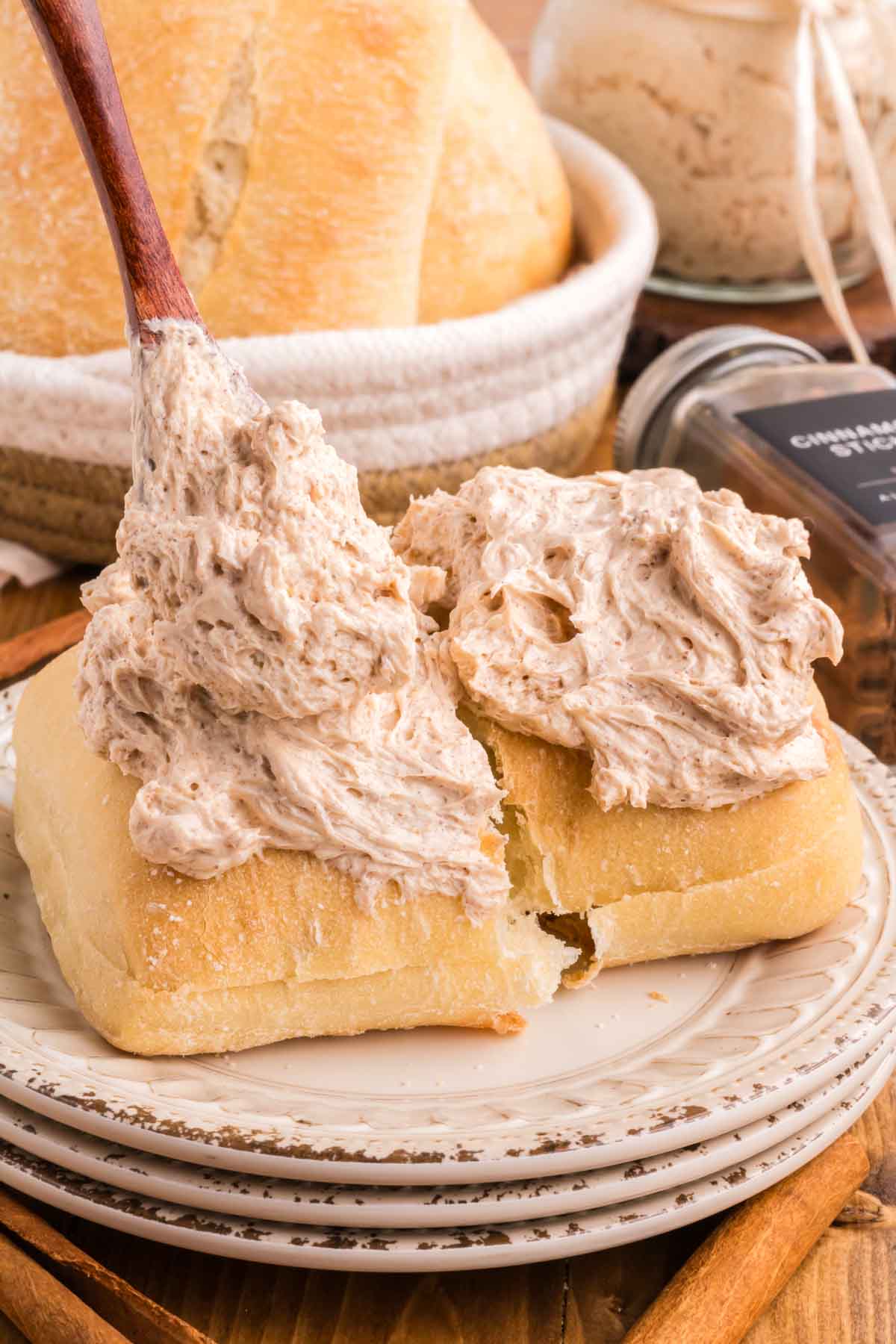 Using a wooden spoon to top a roll with cinnamon honey butter.