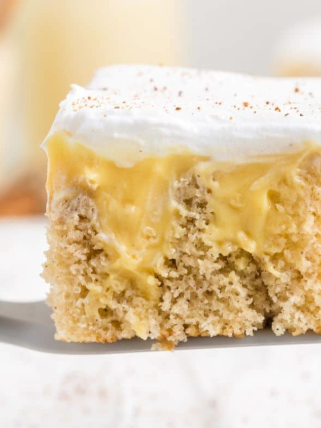 A spatula serving up a slice of eggnog poke cake recipe, revealing the eggnog pudding inside.