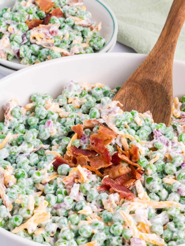 A wooden spoon serving up a scoop of green pea salad.