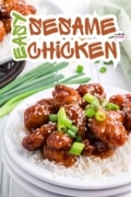 Easy sesame chicken recipe is featured plated on a white plate and garnished with sesame seeds and greed onions.