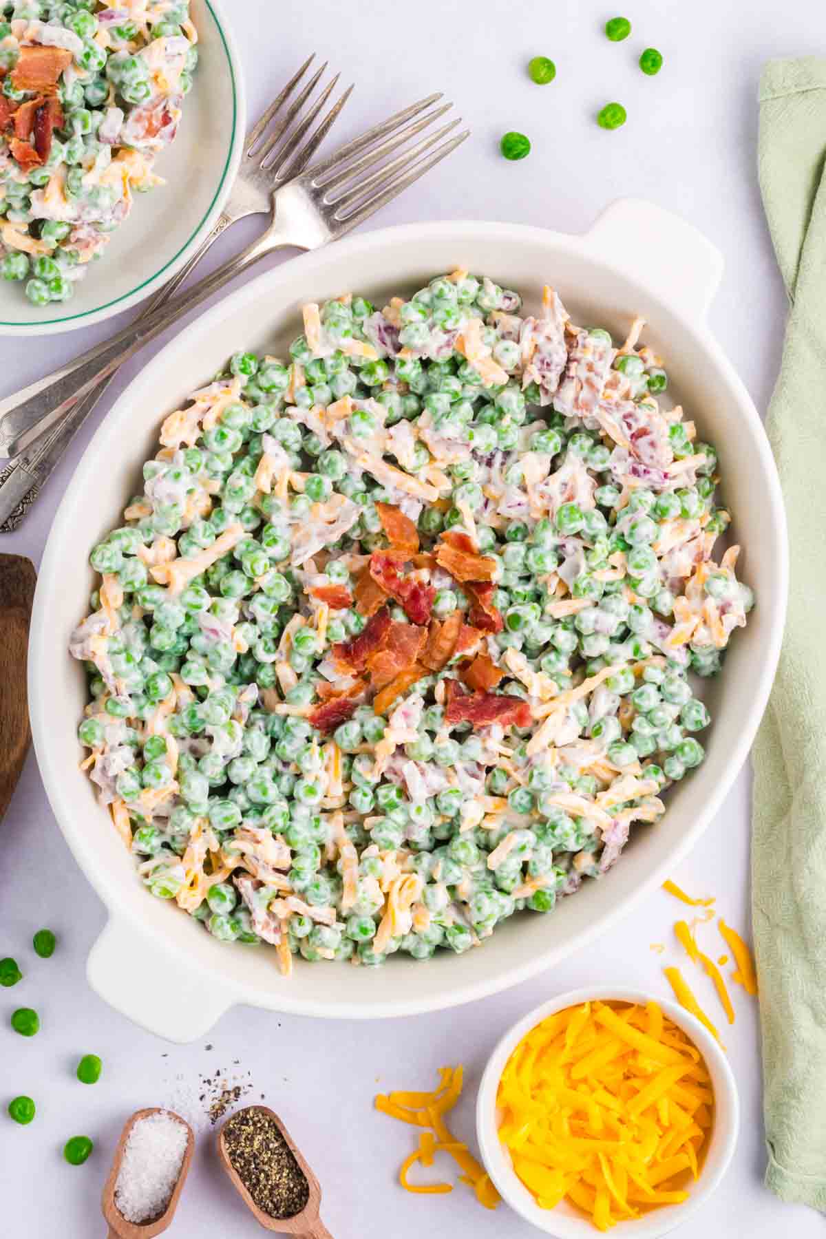 A white oven serving dish filled with green pea salad.