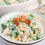 A bowl with a green rim filled a serving of pea salad.