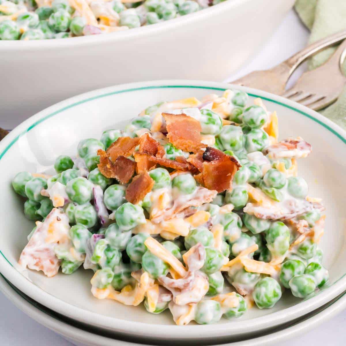 A bowl with a green rim filled a serving of pea salad.