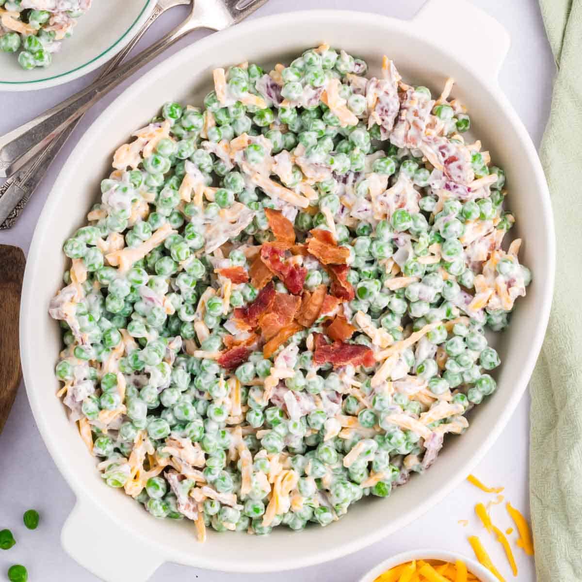 A white oven serving dish filled with green pea salad.