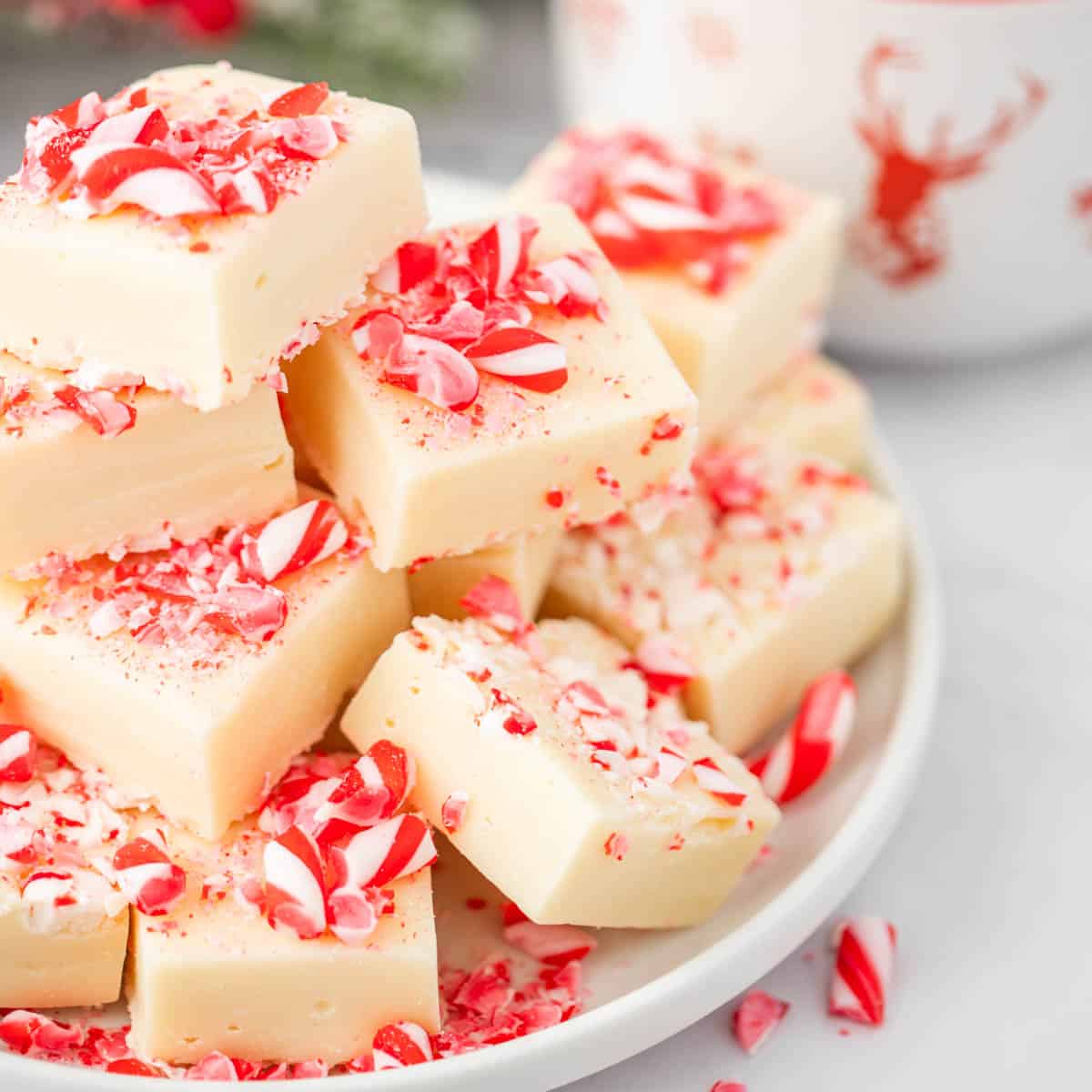 A white plate filled with cut peppermint fudge and scattered candy canes.