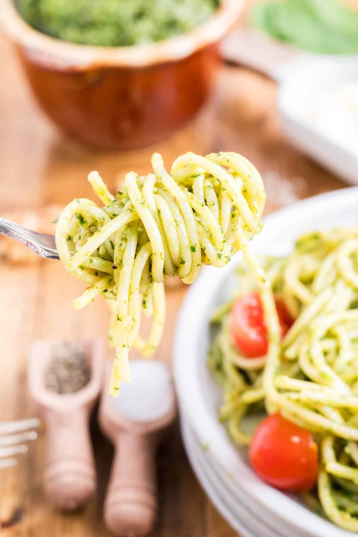 A fork with twirled spaghetti pesto pasta.