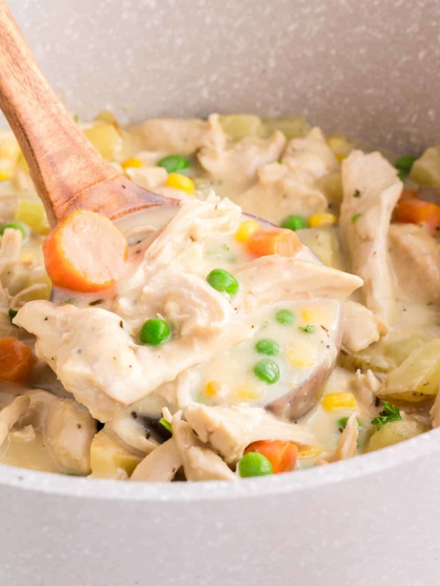 Scooping out a serving of chicken pot pie soup from the pot with a ladle.