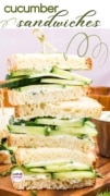 Cucumber sandwich half featured on a wood cuting board and wrapped in brown food safe paper.