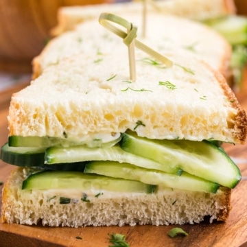 A half of a cucumber sandwich on a wooden tray.
