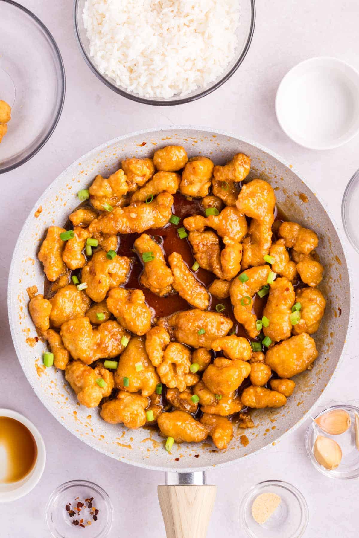 A pan of Chinese crispy honey garlic chicken sprinkled with green onion slices.