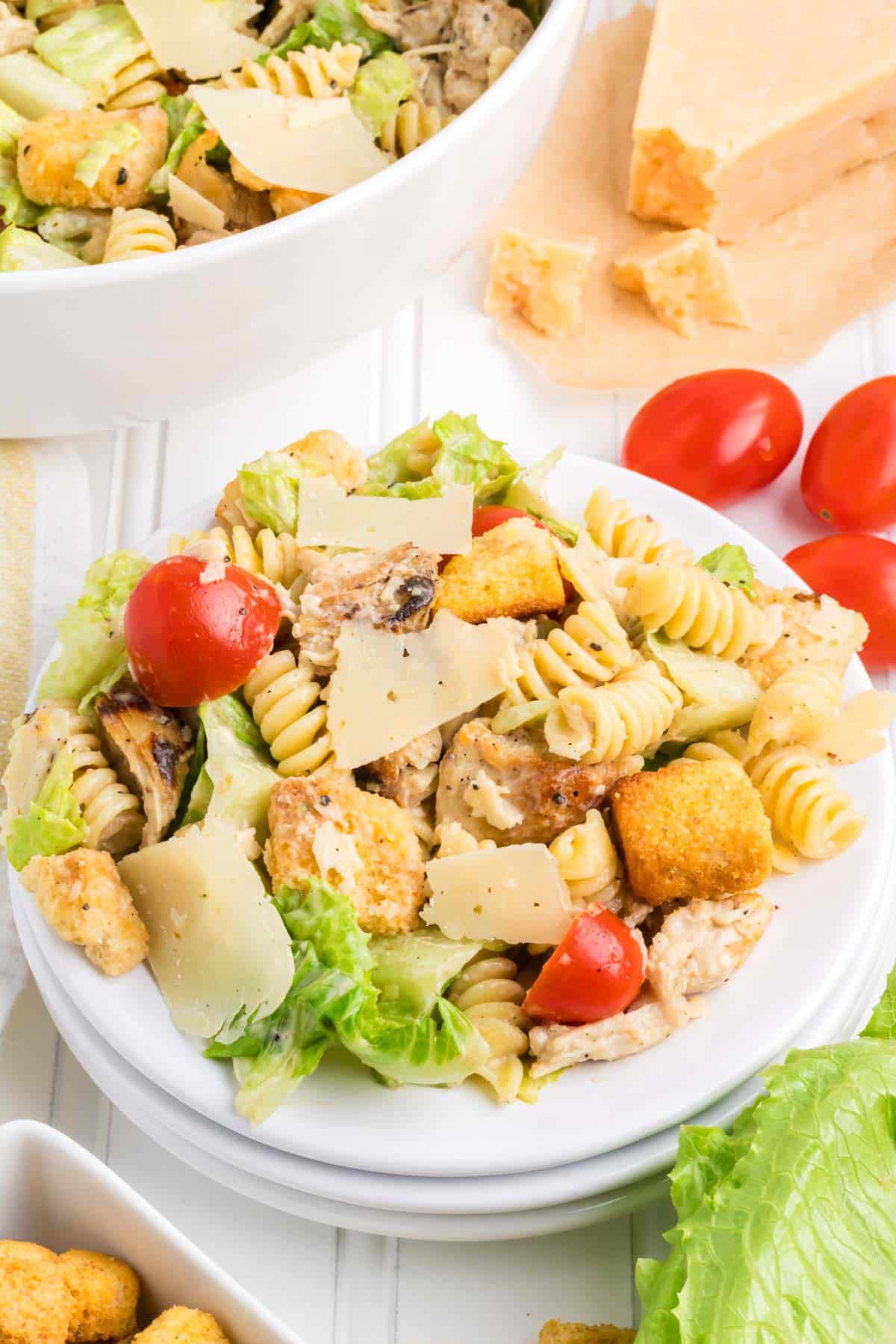 A white serving plate topped with Caesar Salad with chicken and pasta