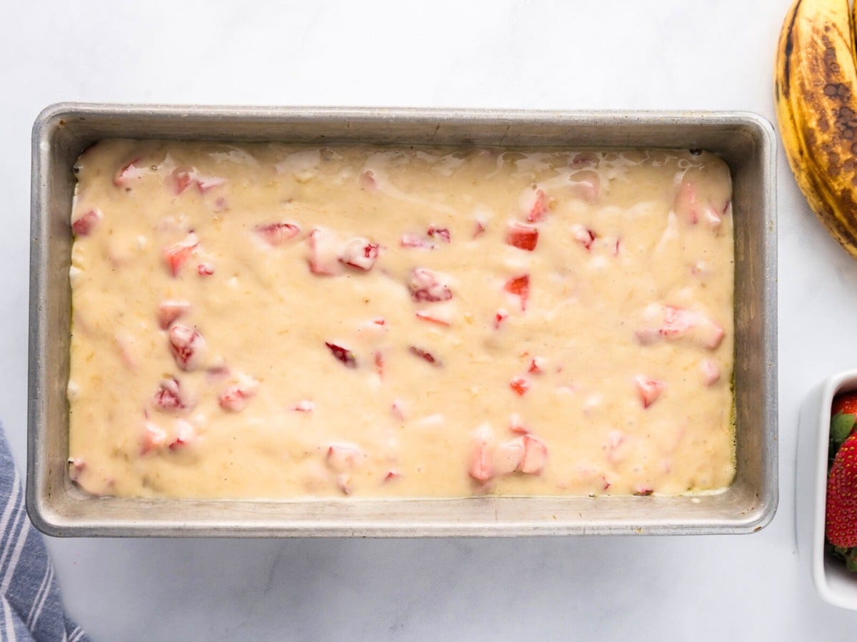 A loaf pan with strawberry banana bread batter.