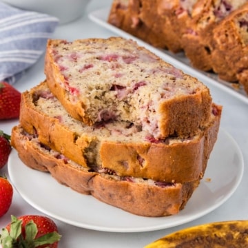 Three slices of strawberry banana bread on a white plate with a bite taken from the top slice.